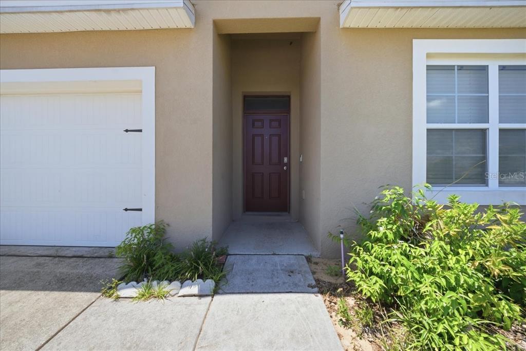 The exterior view shows a tan house with a white garage door and a red door — 750 LAFAYETTE LANE, HAINES CITY, FL