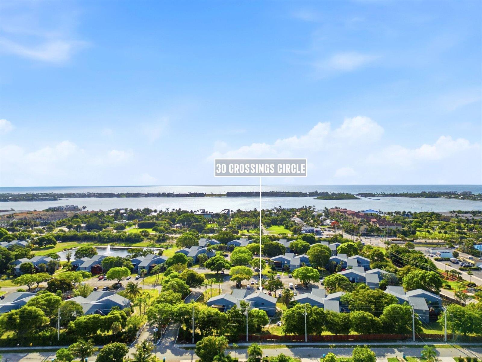 An aerial view shows a residential community with many trees near a large body of water — 30 Crossings Circle # G, Boynton Beach FL 33435, BOYNTON BEACH, FL