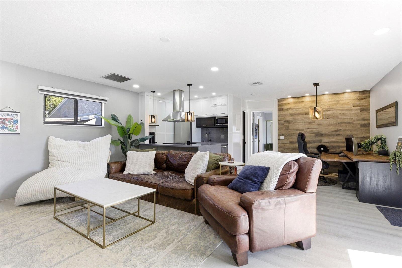A living room with a leather sofa, armchair, coffee table, and an adjacent home office area — 30 Crossings Circle # G, Boynton Beach FL 33435, BOYNTON BEACH, FL