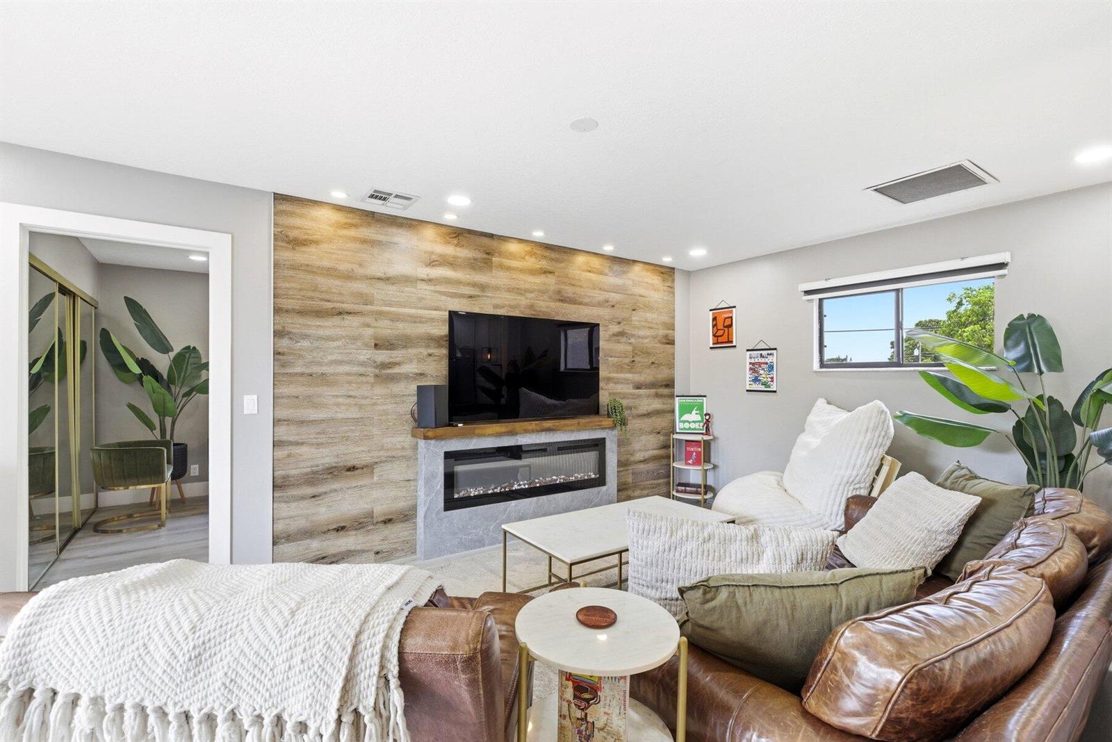 A living room features a wood-paneled accent wall with a fireplace and a leather sofa — 30 Crossings Circle # G, Boynton Beach FL 33435, BOYNTON BEACH, FL