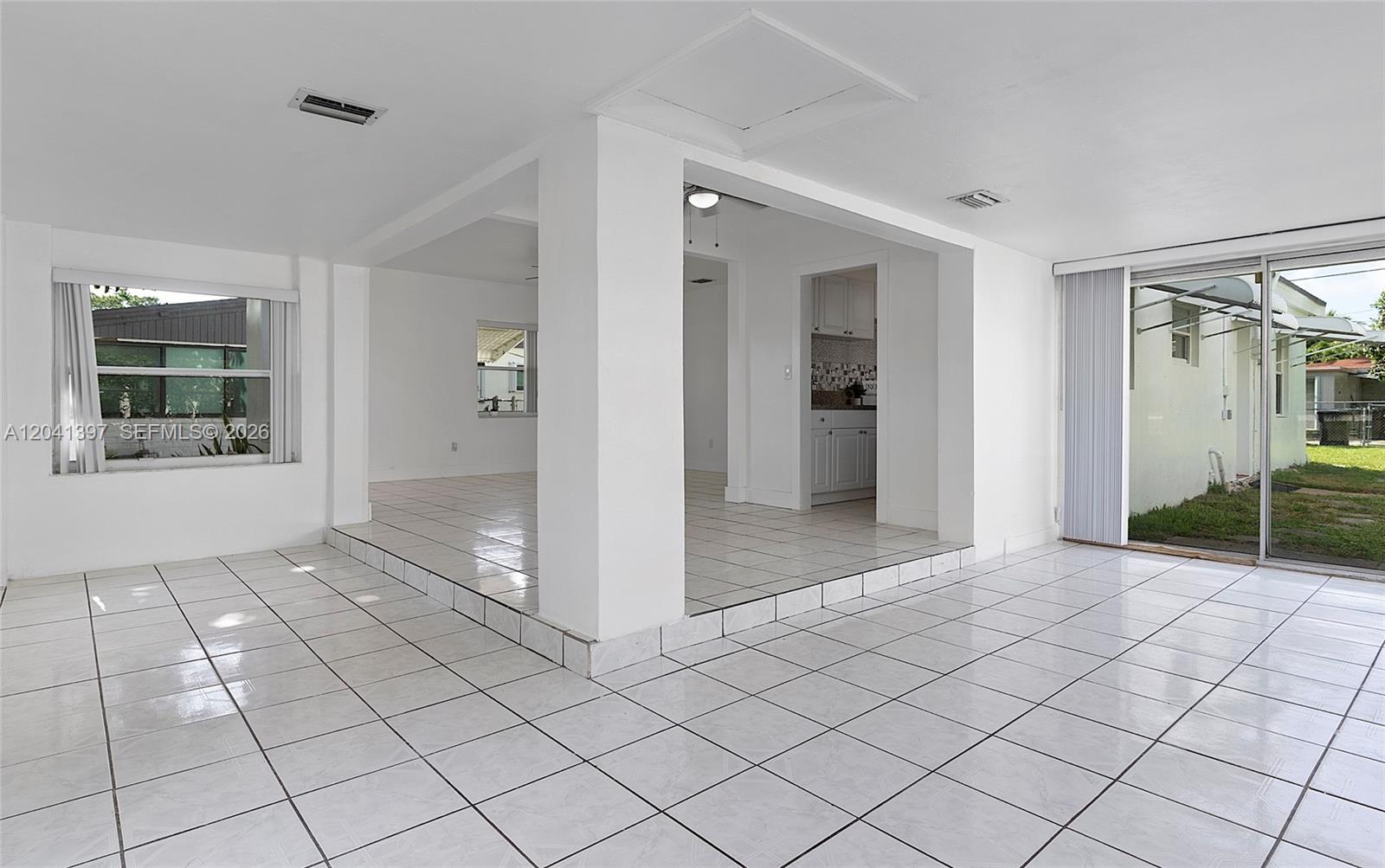 A bright, tiled living area features a sunken floor, white walls, and sliding glass doors — 2024 NE 174th St, North Miami Beach FL 33162, NORTH MIAMI BEACH, FL
