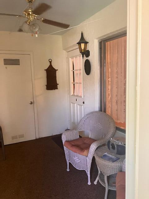 A sunroom features a wicker chair, a side table with a radio, and a ceiling fan — 102 Lake Pine Circle # 2, FL 33463, FL