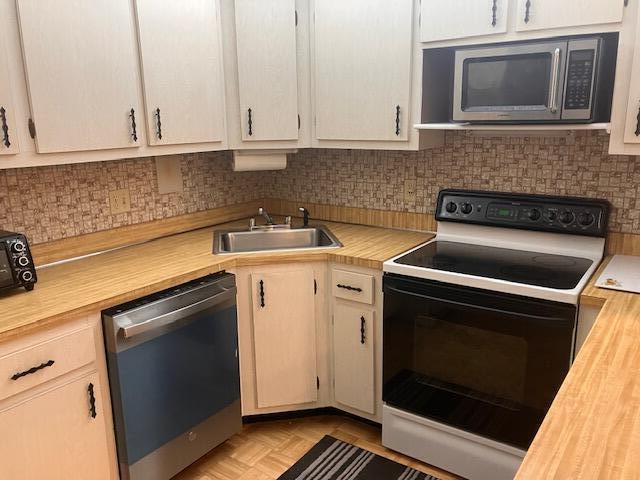 A kitchen features light wood cabinets, a corner sink, a dishwasher, and a black stove — 102 Lake Pine Circle # 2, FL 33463, FL