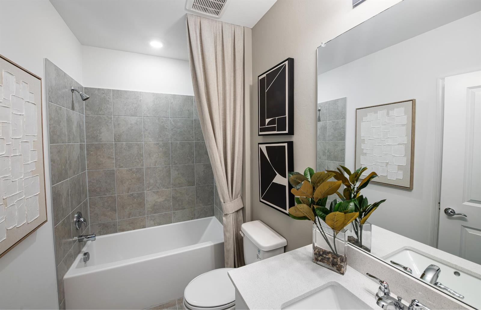 A bathroom features a tiled tub-shower combination, a vanity with a mirror, and wall art — 250 Silent Lake Drive, Lehigh Acres FL 33936, LEHIGH ACRES, FL