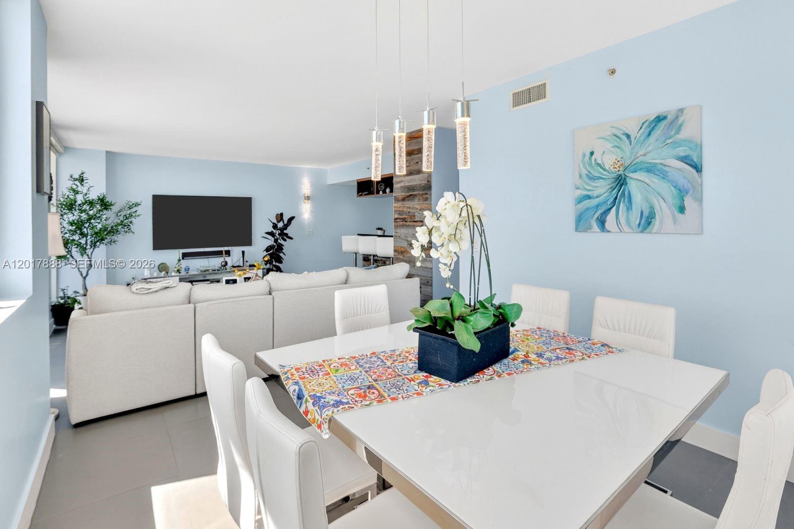 A dining area with a white table and chairs sits before an open-concept living room — 244 Biscayne Blvd # 3602, Miami FL 33132, MIAMI, FL