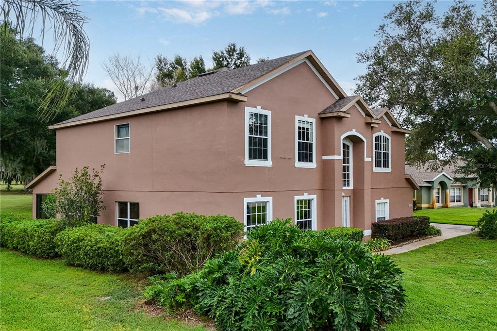 A two-story tan house with a brown shingled roof and white-trimmed windows — 7314 SPRING MOUNTAIN LANE, YALAHA, FL