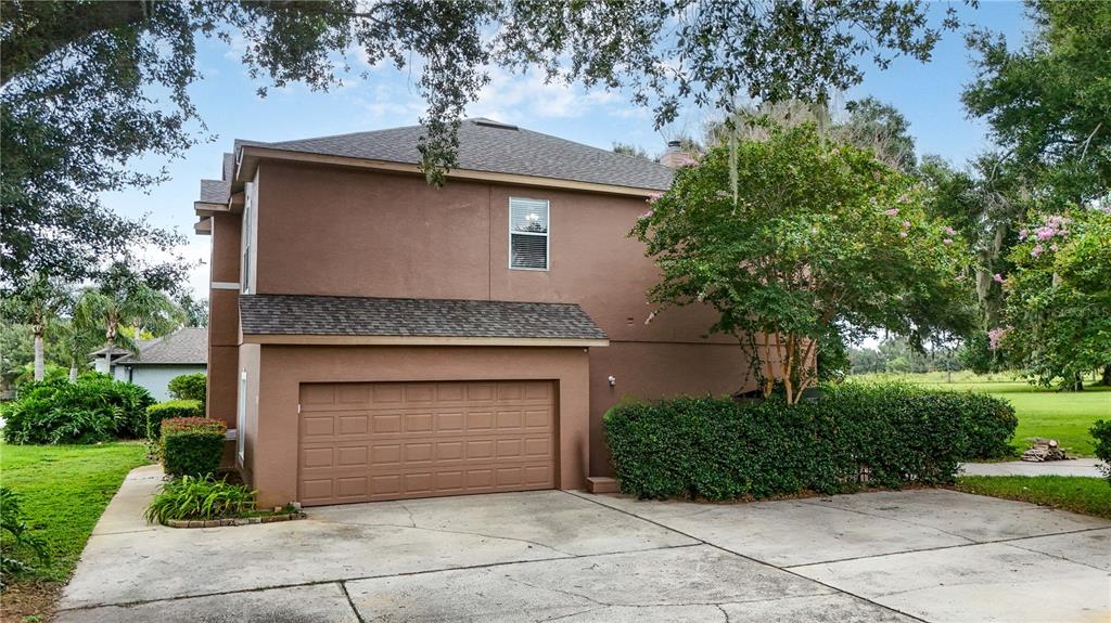 A two-story brown house features a garage, a concrete driveway, and surrounding landscaping — 7314 SPRING MOUNTAIN LANE, YALAHA, FL