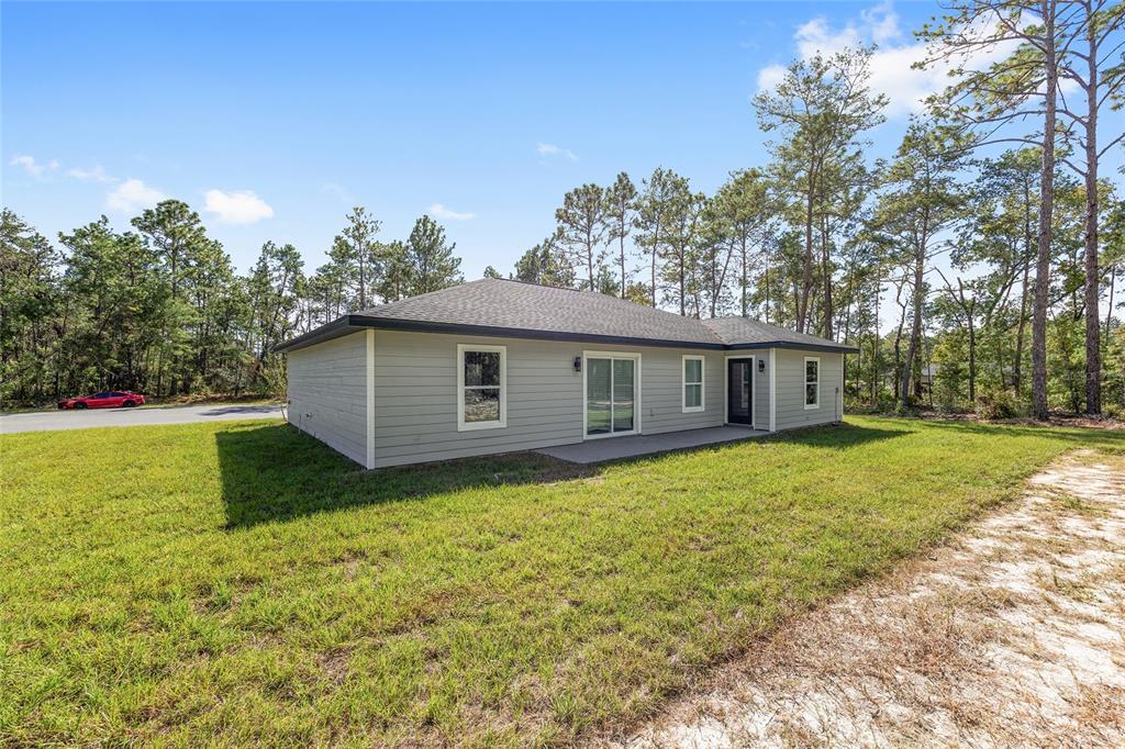 A living room features gray walls, wood-look flooring, a sofa, two chairs, and a wall-mounted television — 24303 SW SAILBOAT DRIVE, DUNNELLON, FL