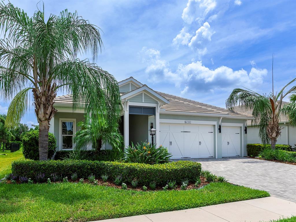 A single-story house with a light green exterior, a tiled roof, and a three-car garage — 8282 GRANDE SHORES DRIVE, SARASOTA, FL