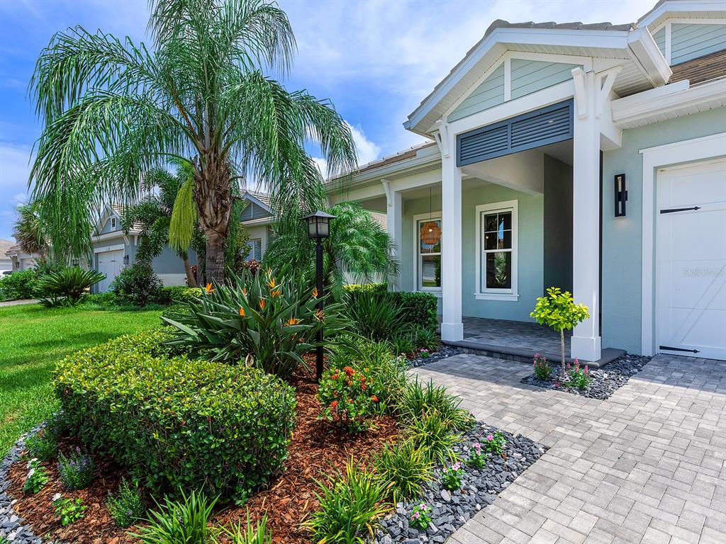 A light blue house exterior features a paved walkway, palm tree, and landscaped front yard — 8282 GRANDE SHORES DRIVE, SARASOTA, FL