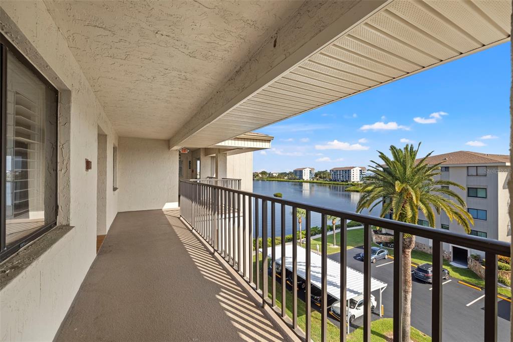 An outdoor balcony with a metal railing overlooks a lake, parking lot, and palm tree — 8150 BRENT STREET UNIT 747, PORT RICHEY, FL