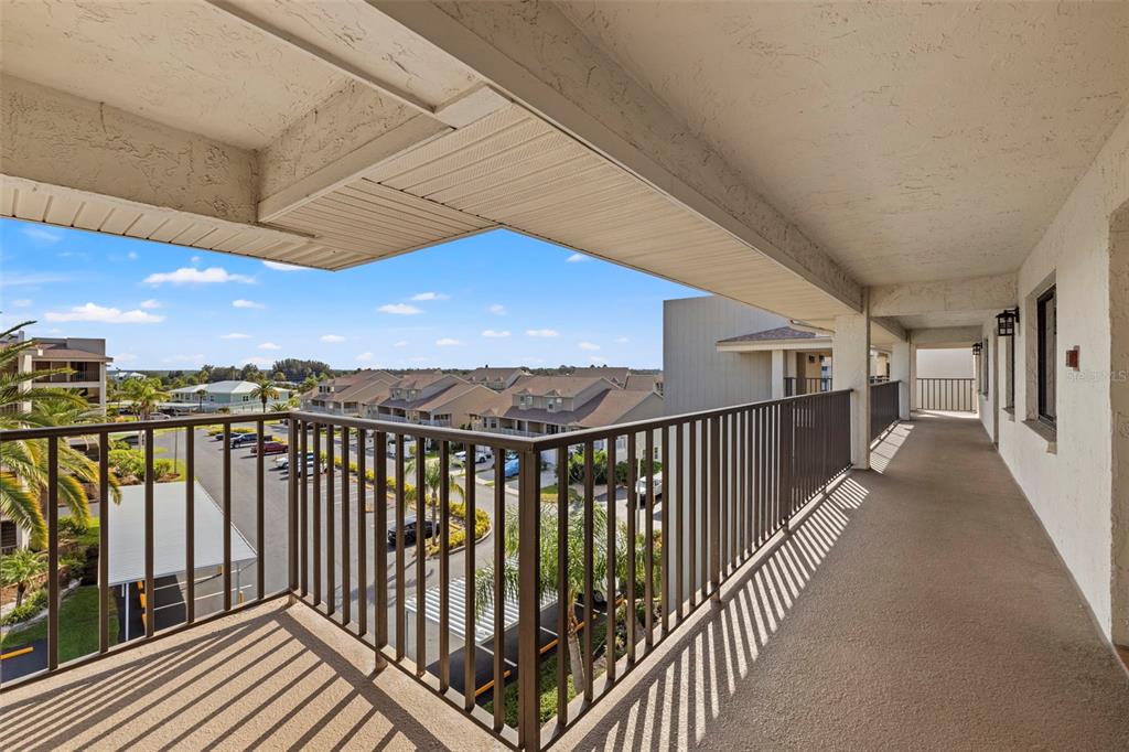 An elevated outdoor balcony with a metal railing overlooks a parking lot and residential buildings — 8150 BRENT STREET UNIT 747, PORT RICHEY, FL