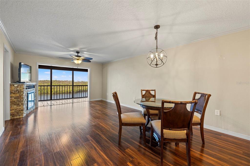 A dining area with a glass table, wooden chairs, dark wood floors, and a balcony view — 8150 BRENT STREET UNIT 747, PORT RICHEY, FL