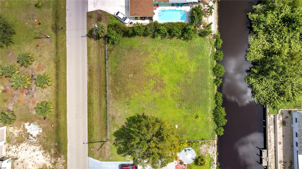 An aerial view shows a vacant rectangular lot situated between a road and a canal — 321 POMPANO TERRACE, PUNTA GORDA, FL
