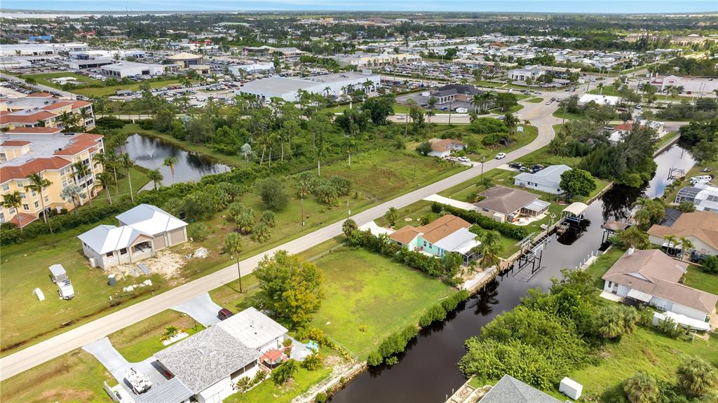 An aerial view shows residential houses, a canal, and a large undeveloped lot — 321 POMPANO TERRACE, PUNTA GORDA, FL