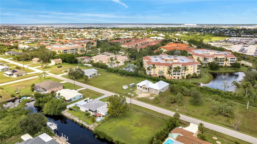 An aerial view shows a residential neighborhood with houses, apartment buildings, and a canal — 321 POMPANO TERRACE, PUNTA GORDA, FL