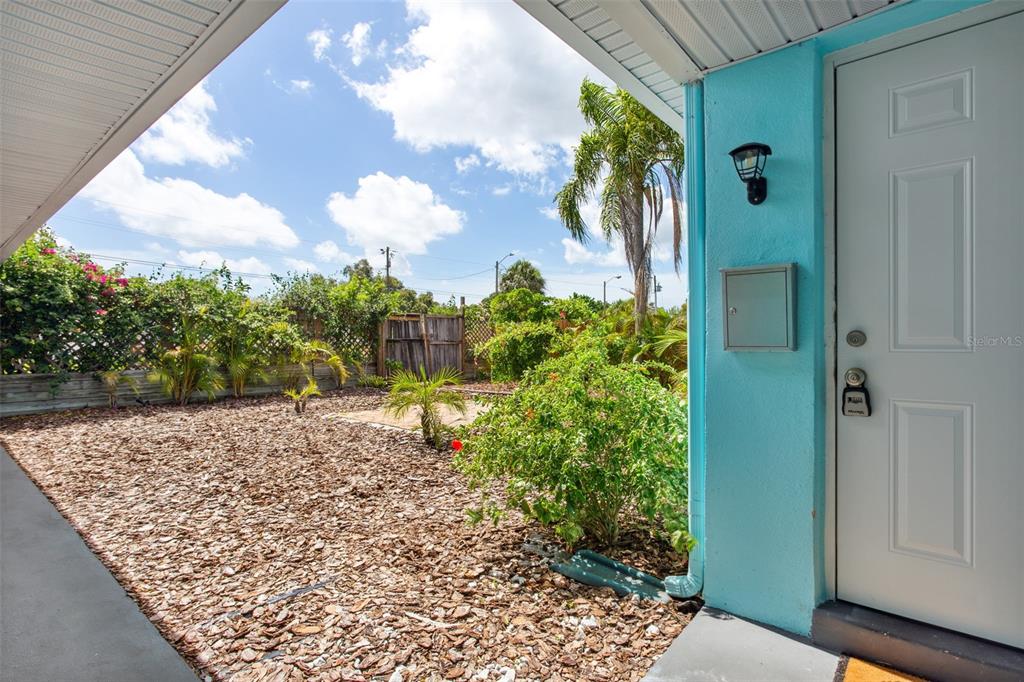 A view from a covered porch looking out onto a landscaped yard with wood mulch — 1230 70TH STREET N, ST PETERSBURG, FL