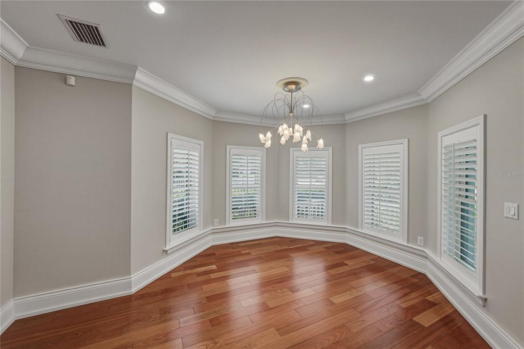 A sitting room features four beige armchairs, a round wooden coffee table, and plantation shutters — 3001 W SAN RAFAEL STREET, TAMPA, FL