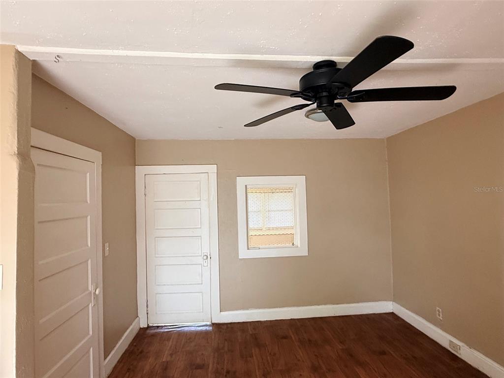 An empty room with tan walls, wood-look flooring, a ceiling fan, and two white doors — 1648 27TH AVENUE N UNIT 2, ST PETERSBURG, FL