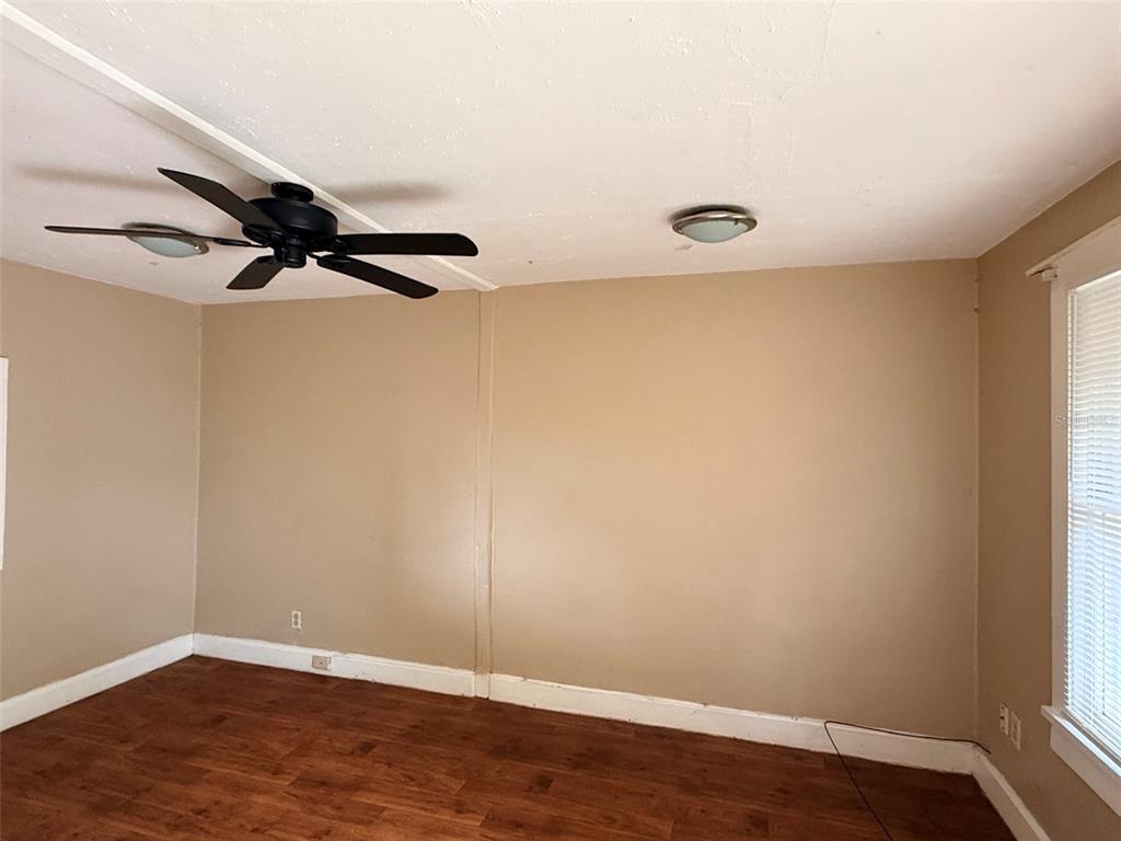 An empty room features wood-look flooring, beige walls, a ceiling fan, and a window — 1648 27TH AVENUE N UNIT 2, ST PETERSBURG, FL