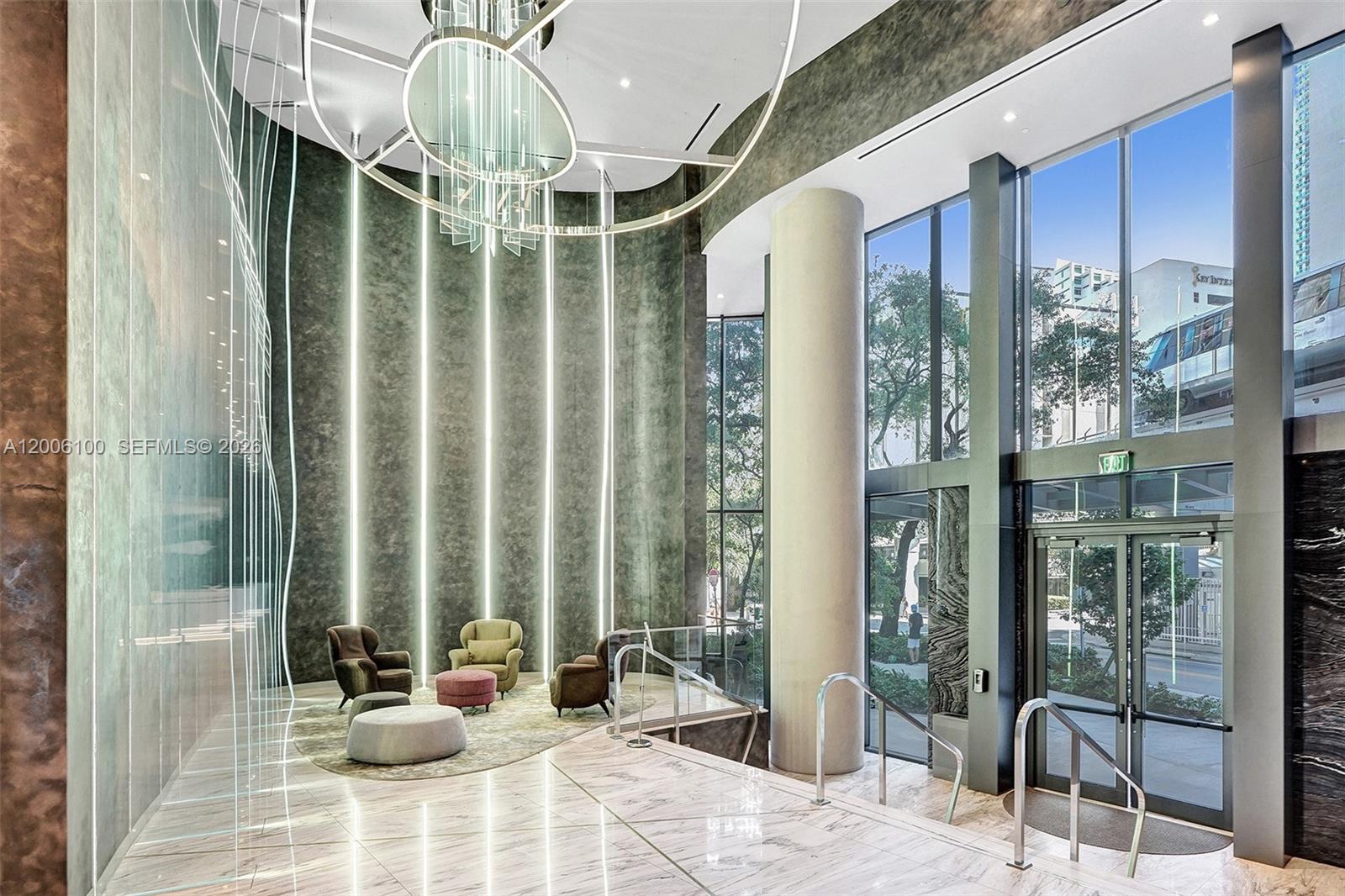 A modern building lobby features a high ceiling, marble floors, vertical lighting, and glass walls — 1000 Brickell Plaza, Miami FL 33131, MIAMI, FL