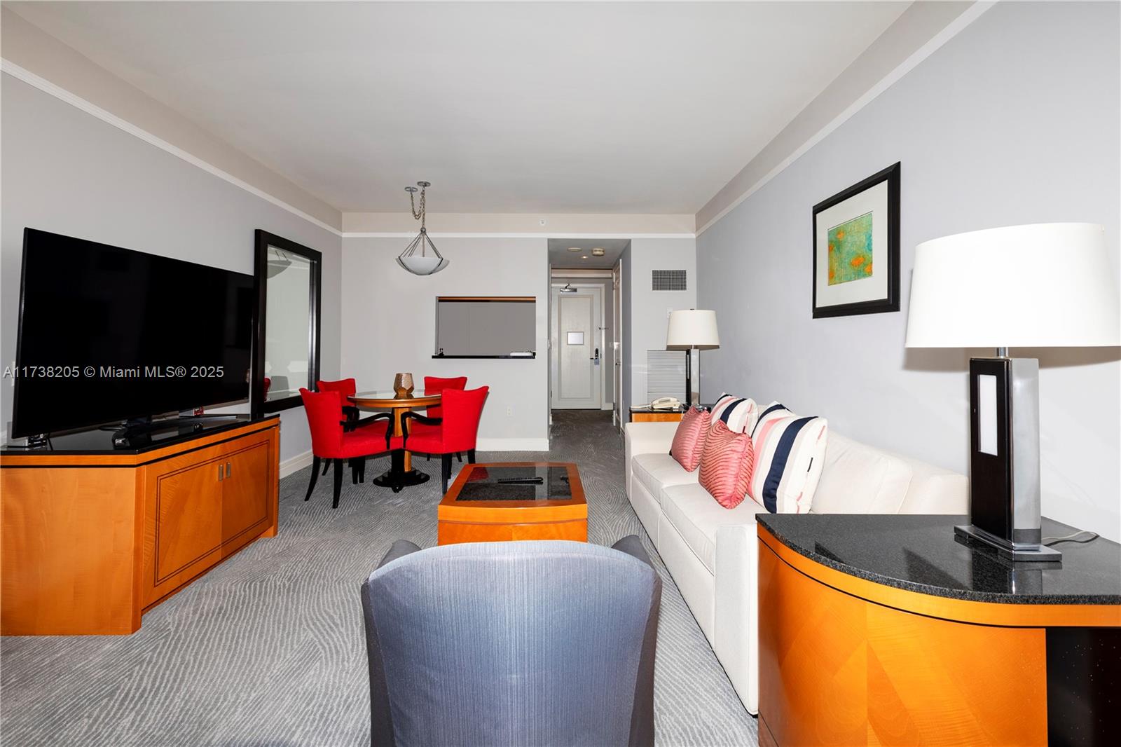 A living room features a white sofa, red dining chairs, a television, and patterned carpeting — 1435 Brickell Ave # 3010, Miami FL 33131, MIAMI, FL