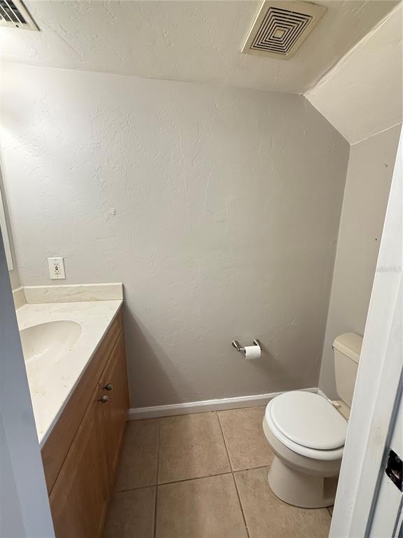 A bathroom features a wooden vanity with a white countertop, a toilet, and tile flooring — 630 SW 10TH LANE UNIT 2, GAINESVILLE, FL