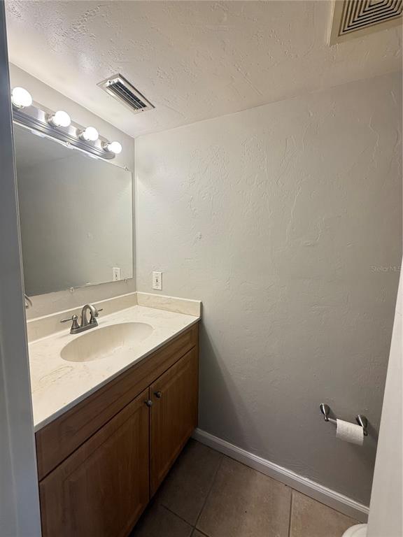 A bathroom features a wooden vanity with a light countertop, a mirror, and gray walls — 630 SW 10TH LANE UNIT 2, GAINESVILLE, FL