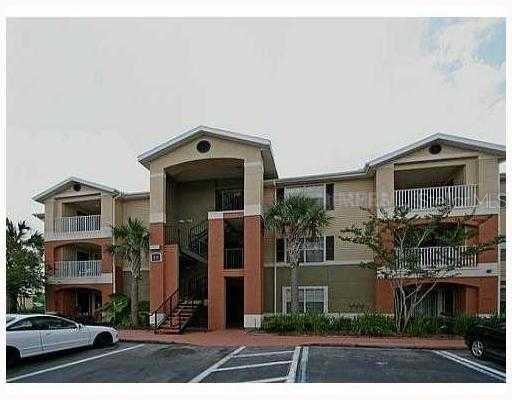 A three-story apartment building with tan and orange stucco walls and white balcony railings — 1999 SUMMER CLUB DRIVE UNIT 313, OVIEDO, FL