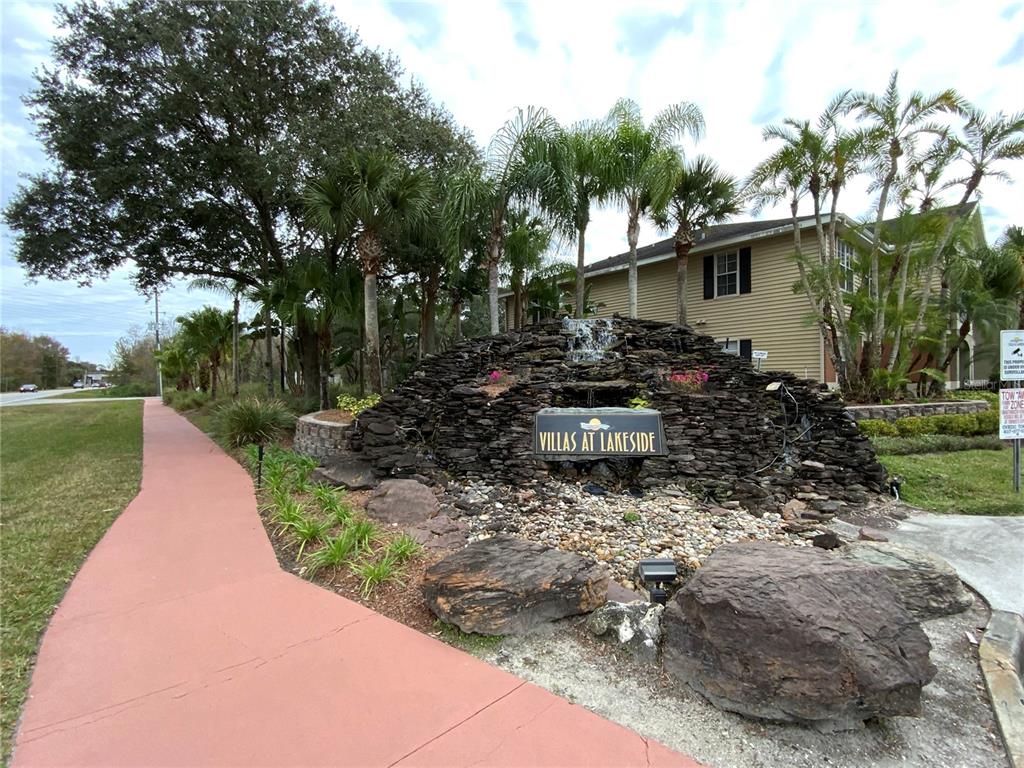 A stone water feature with a sign stands in front of a tan apartment building — 1999 SUMMER CLUB DRIVE UNIT 313, OVIEDO, FL
