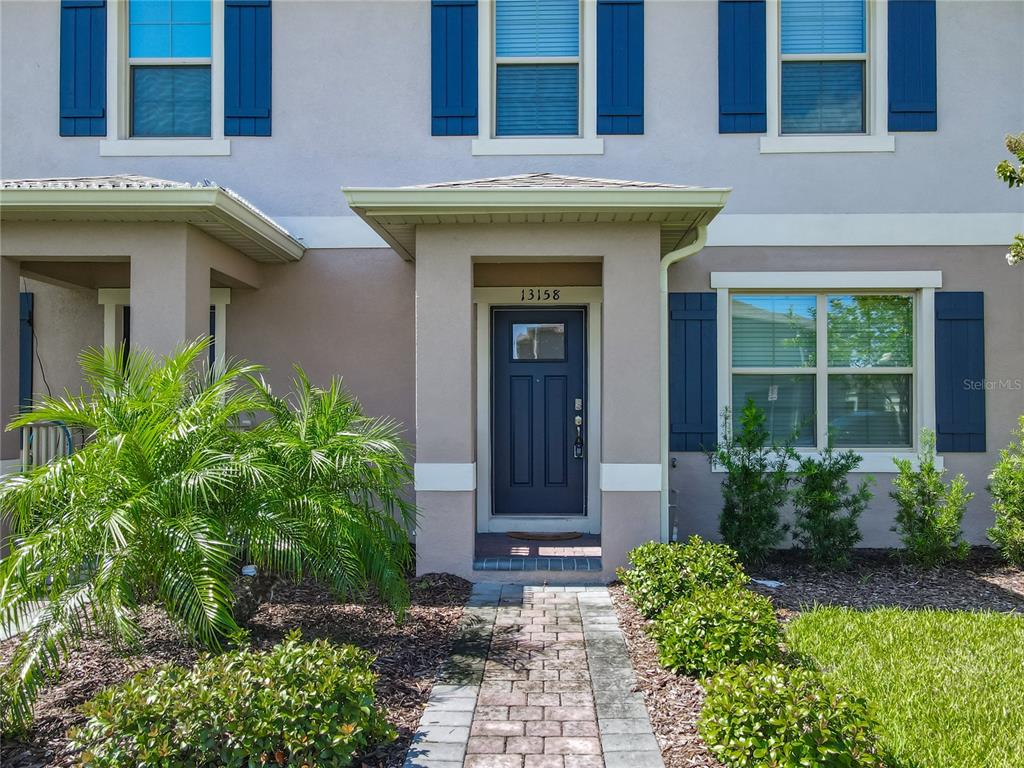 A two-story townhouse exterior features a dark blue front door and blue window shutters — 13158 BOUNTY AVENUE, WINTER GARDEN, FL