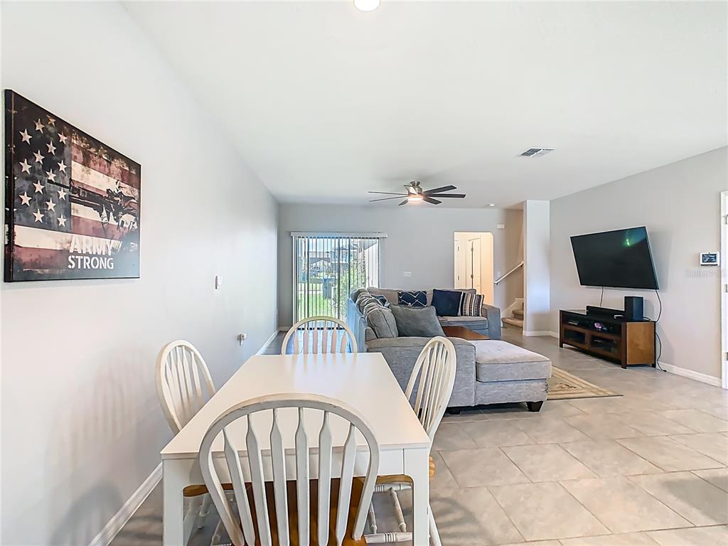 A dining area with a white table and chairs opens into a living room — 13158 BOUNTY AVENUE, WINTER GARDEN, FL