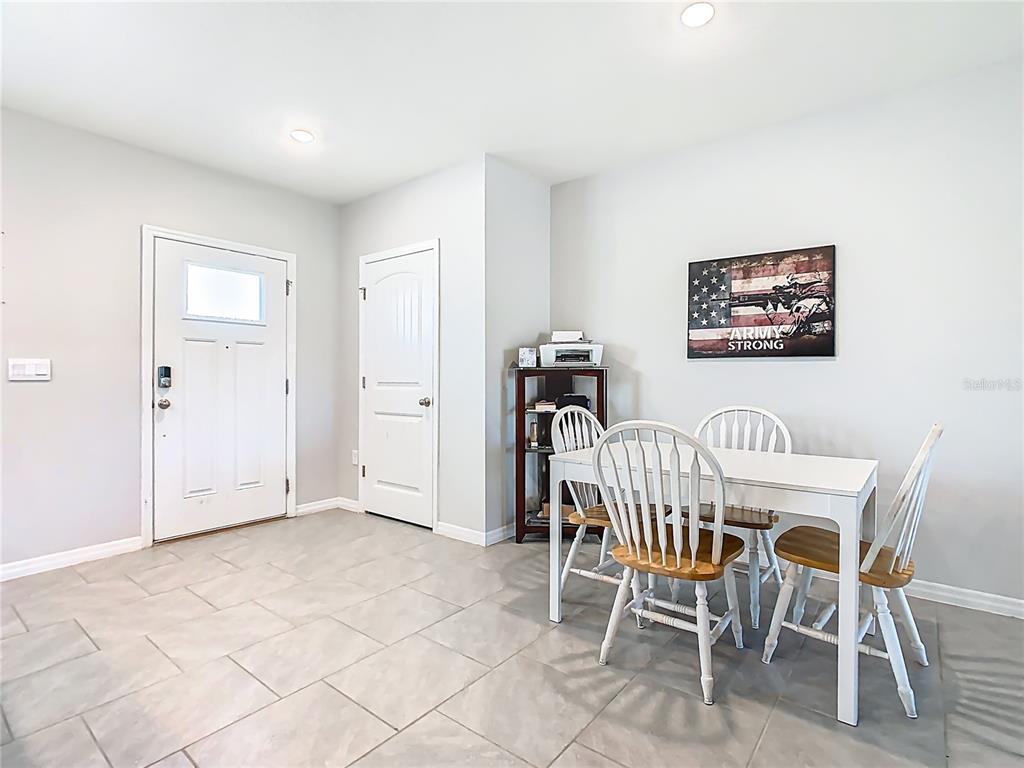 A dining area features a white table with four chairs, tile flooring, and a front door — 13158 BOUNTY AVENUE, WINTER GARDEN, FL