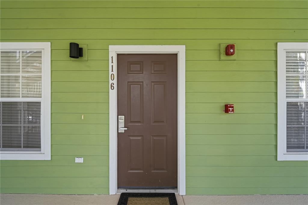 A brown front door with the number 1106 is set into a light green exterior wall — 1106 GRAN BAHAMA BOULEVARD UNIT 1106, DAVENPORT, FL