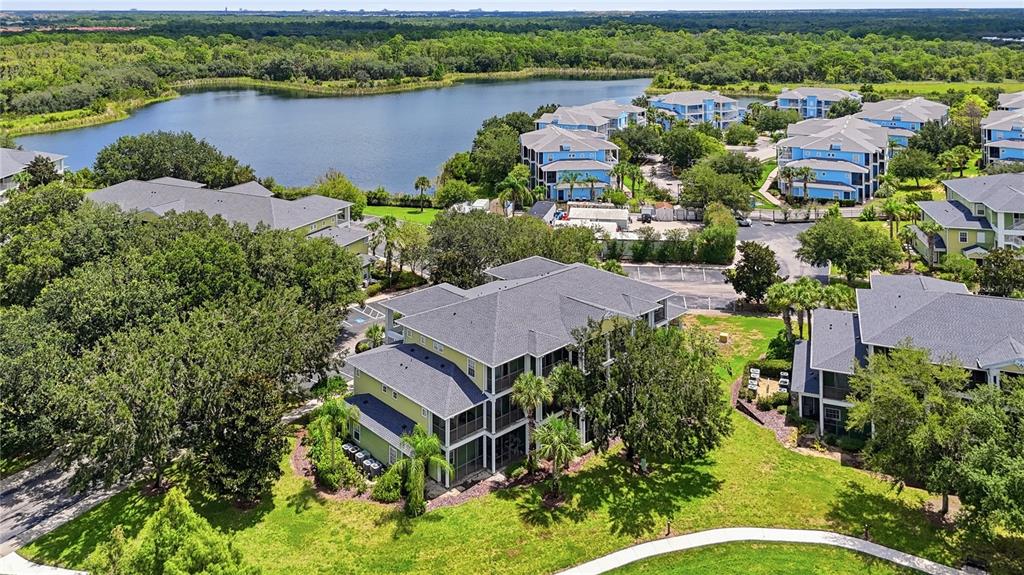 An aerial view shows multi-story apartment buildings surrounded by lush trees and a large lake — 1106 GRAN BAHAMA BOULEVARD UNIT 1106, DAVENPORT, FL