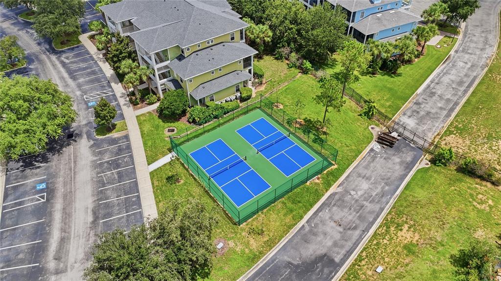 An aerial view shows a residential building next to two fenced pickleball courts — 1106 GRAN BAHAMA BOULEVARD UNIT 1106, DAVENPORT, FL