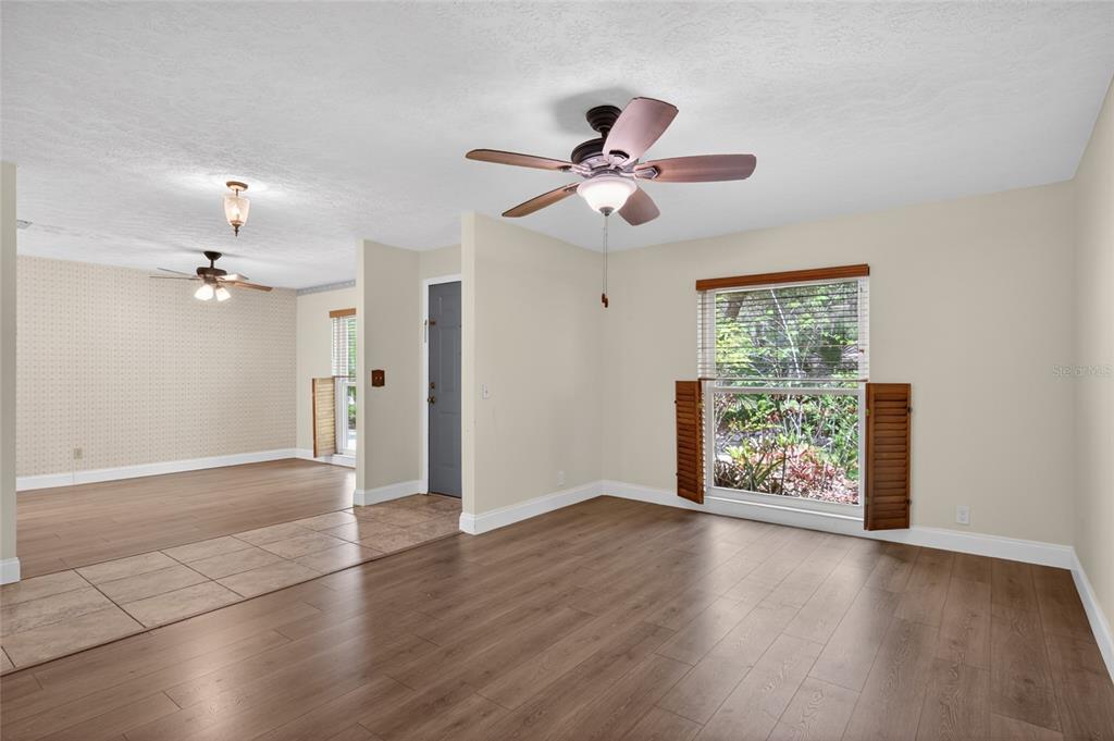 A living room with wood-look flooring, a ceiling fan, and a view of outdoor greenery — 901 W RIVER DRIVE, TEMPLE TERRACE, FL
