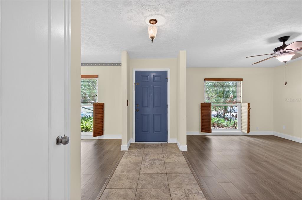 An entryway with a blue front door, tile flooring, and wood-look laminate in adjacent rooms — 901 W RIVER DRIVE, TEMPLE TERRACE, FL
