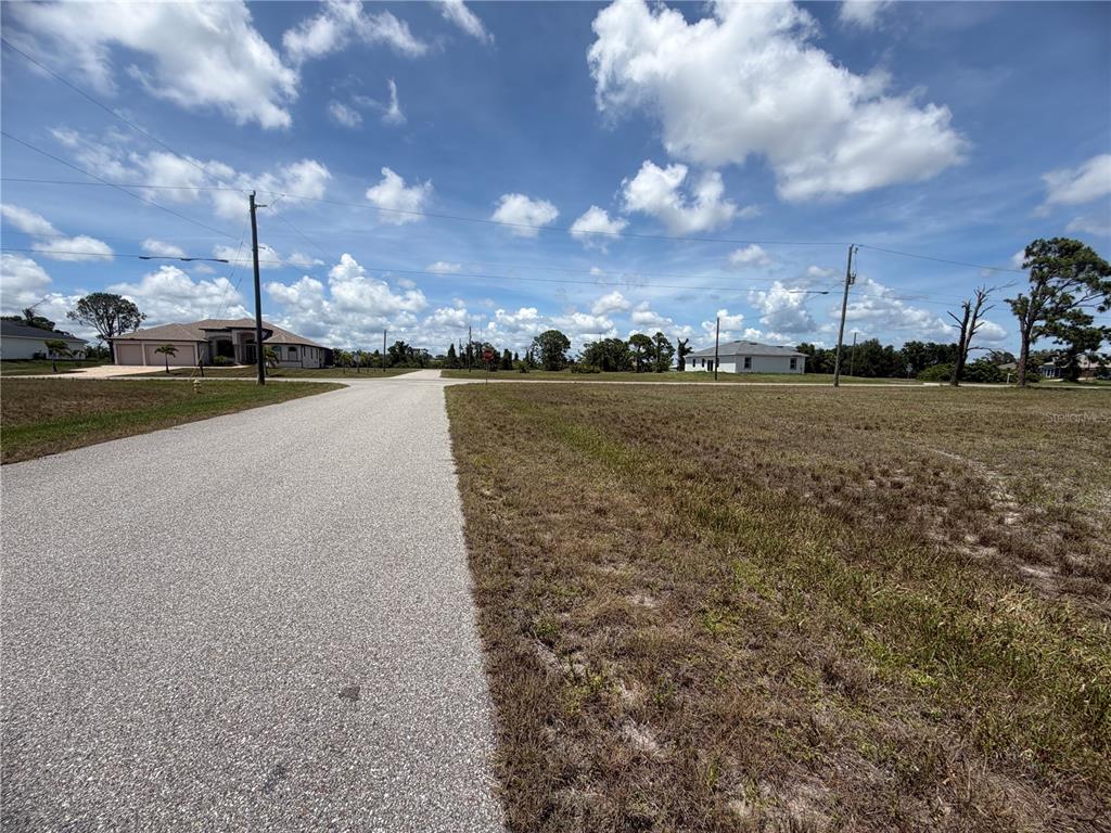 A paved road leads toward a residential intersection with vacant lots and nearby houses — 15 TIDE COURT, PLACIDA, FL