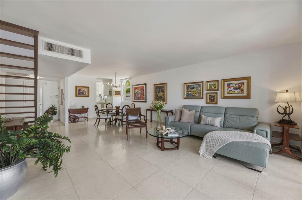 A spacious living and dining area with light tile floors, a blue sofa, and artwork — 16 CARRION COURT UNIT 24, SAN JUAN, PR