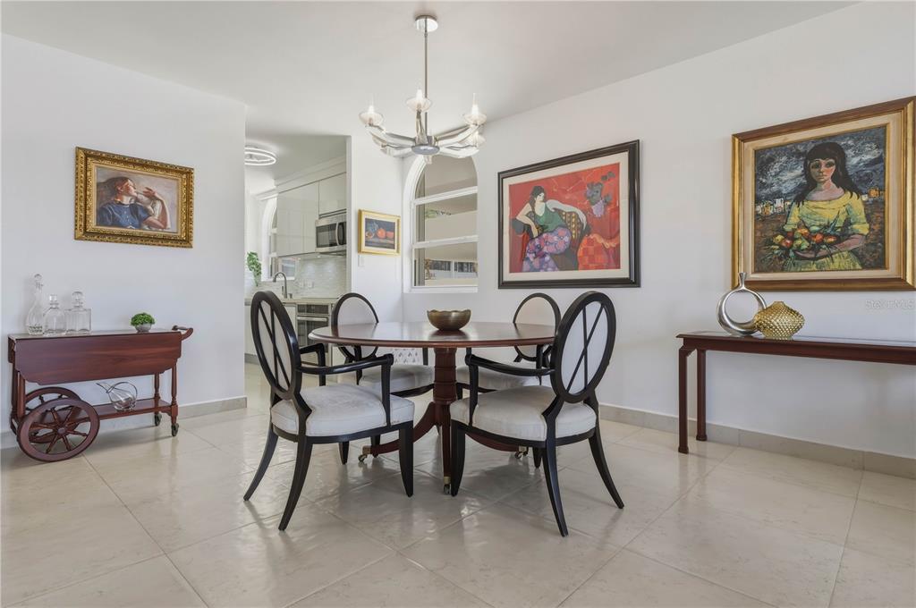 A dining room features a round wooden table, four chairs, and artwork on white walls — 16 CARRION COURT UNIT 24, SAN JUAN, PR