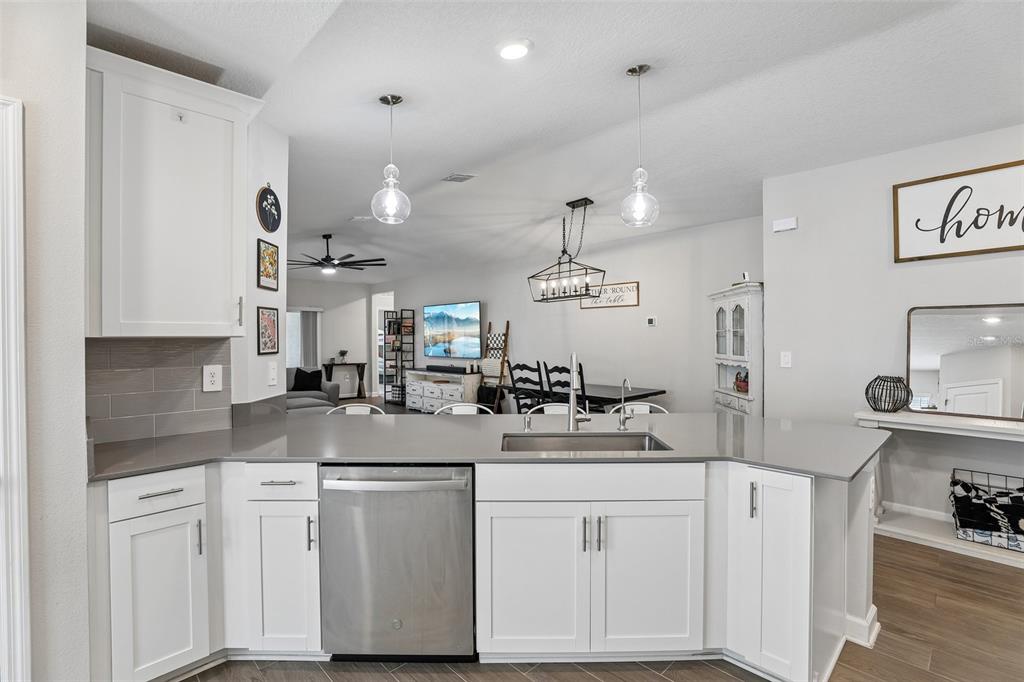 A kitchen with white cabinets, gray countertops, and a view into the dining area — 5671 WOOD BRIDGE PLACE, ST CLOUD, FL
