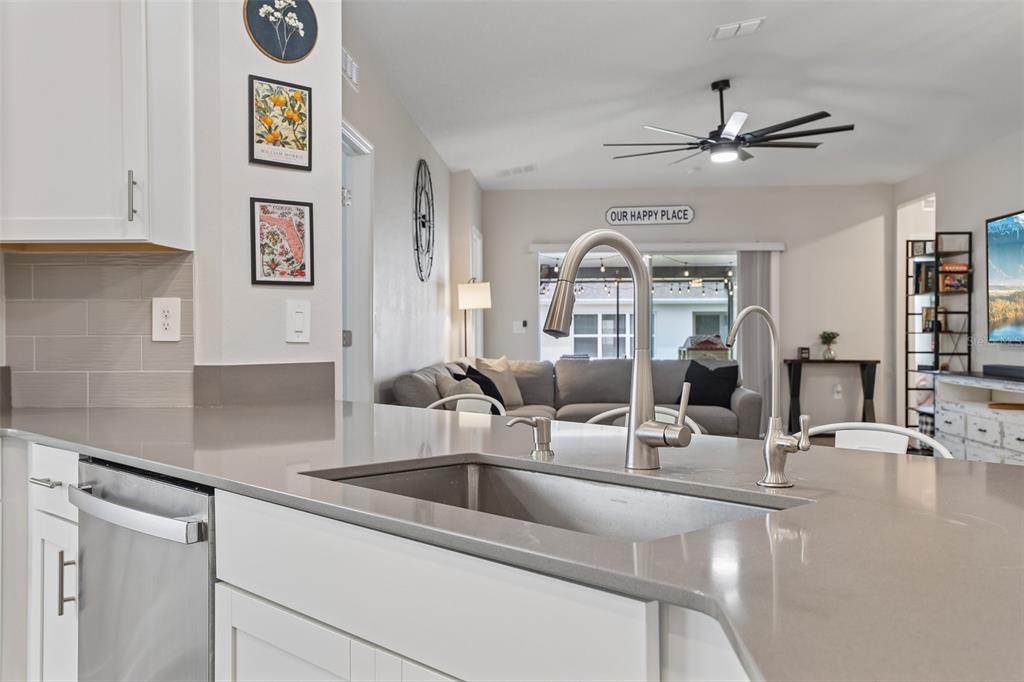 A kitchen island with a stainless steel sink overlooks a living room with a sofa — 5671 WOOD BRIDGE PLACE, ST CLOUD, FL