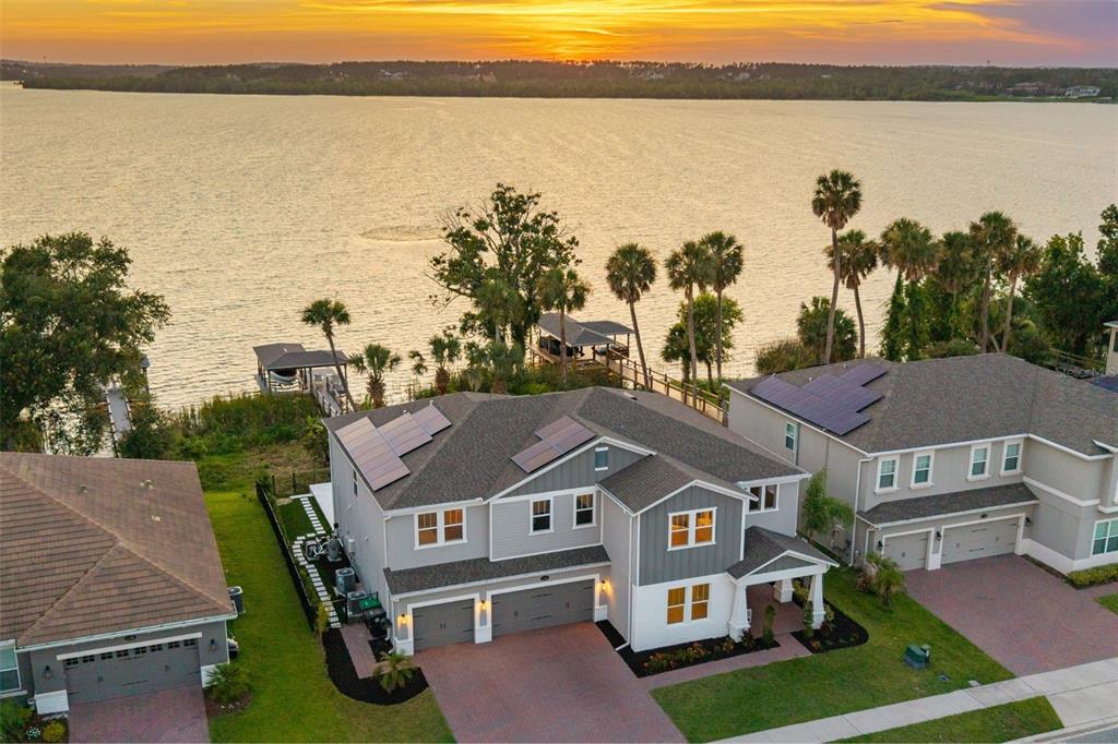 An aerial view of a two-story house with solar panels, a garage, and lakefront access — 1144 HULL ISLAND DRIVE, WINTER GARDEN, FL