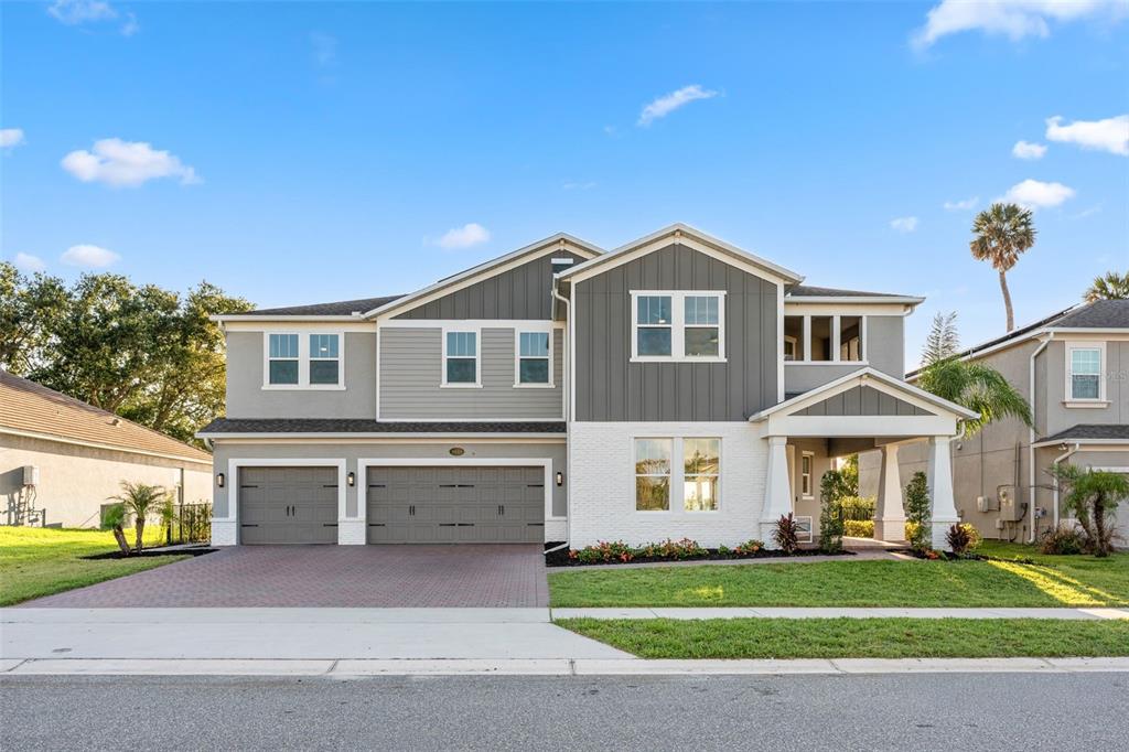 A two-story suburban house with a three-car garage, gray siding, and a white brick facade — 1144 HULL ISLAND DRIVE, WINTER GARDEN, FL