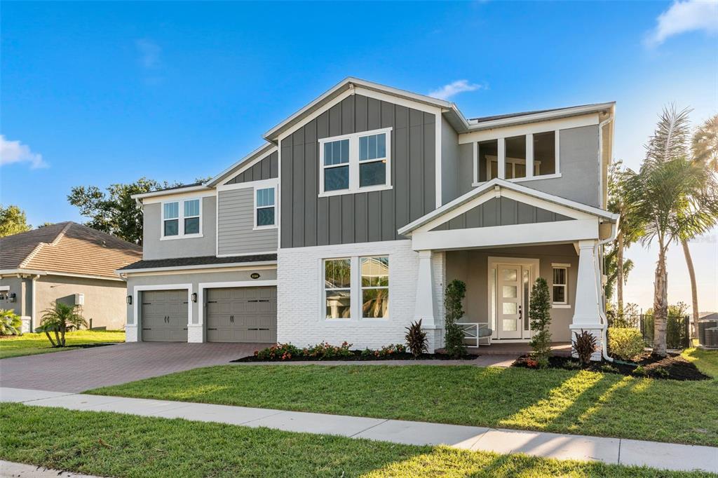 A two-story house features a white brick facade, gray vertical siding, and a two-car garage — 1144 HULL ISLAND DRIVE, WINTER GARDEN, FL