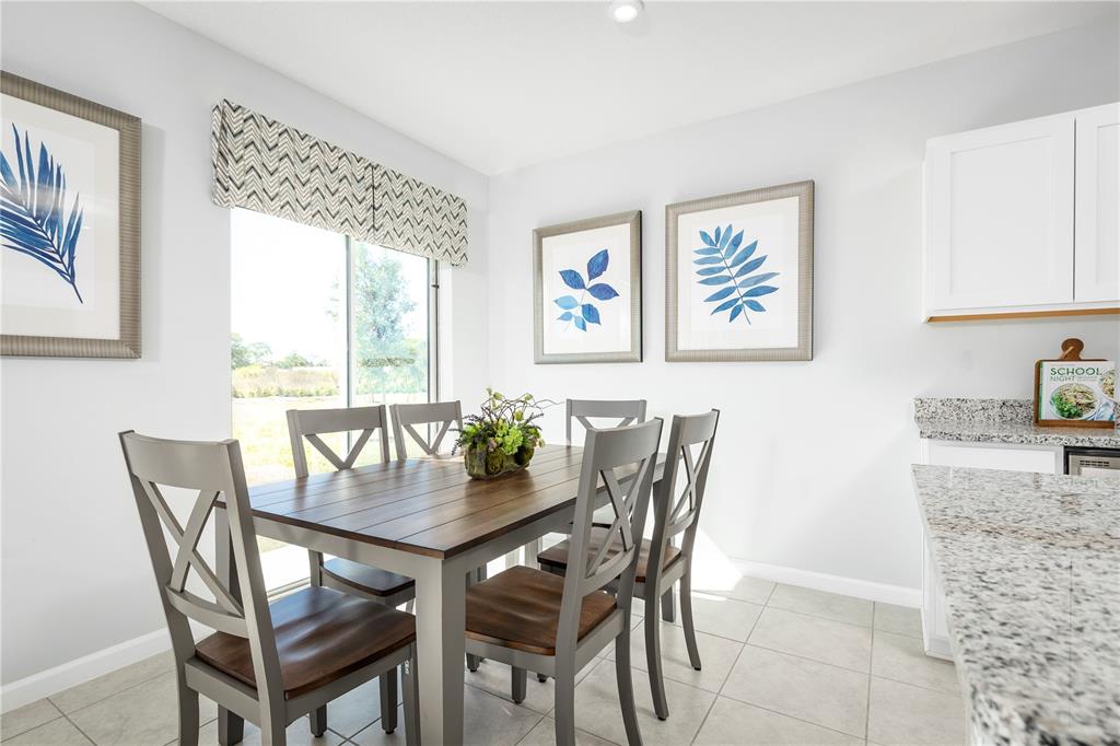A dining area features a wooden table, four gray chairs, and framed botanical wall art — 4826 RIVER BIRCH BEND, LAKELAND, FL