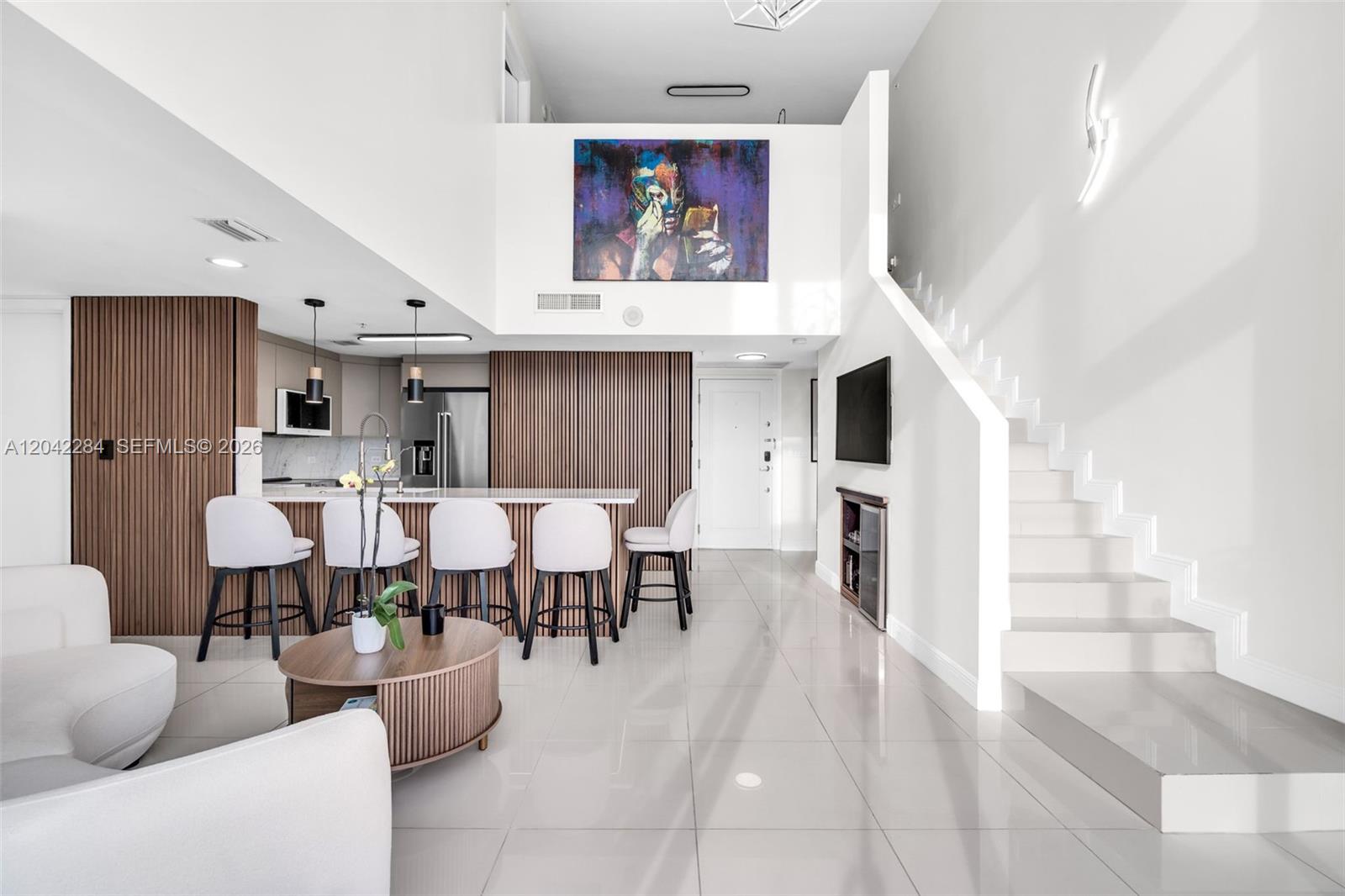 A modern living room features a kitchen island, wood-slat walls, and a staircase — 1861 NW S River Dr, Miami FL 33125, MIAMI, FL