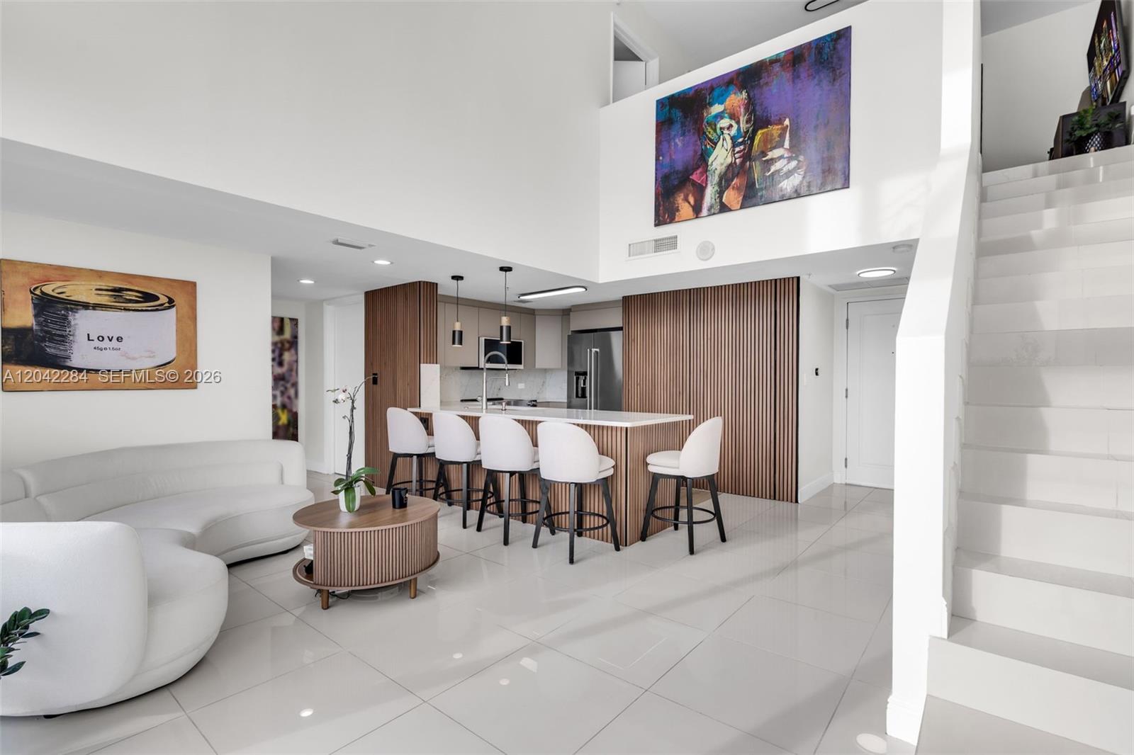 A modern open-concept living area features a kitchen with wood-slat walls and white bar stools — 1861 NW S River Dr, Miami FL 33125, MIAMI, FL