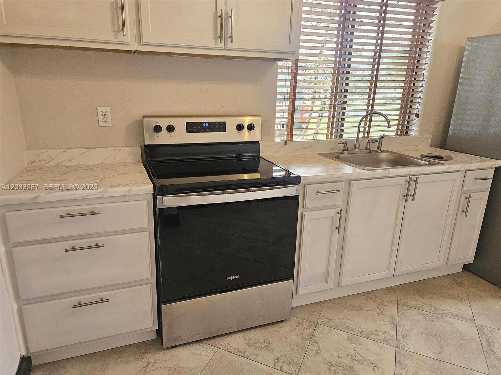 A kitchen features white cabinets, marble-look countertops, a stainless steel stove, and a sink — 12975 SW 189th St # 1, Miami FL 33177, MIAMI, FL